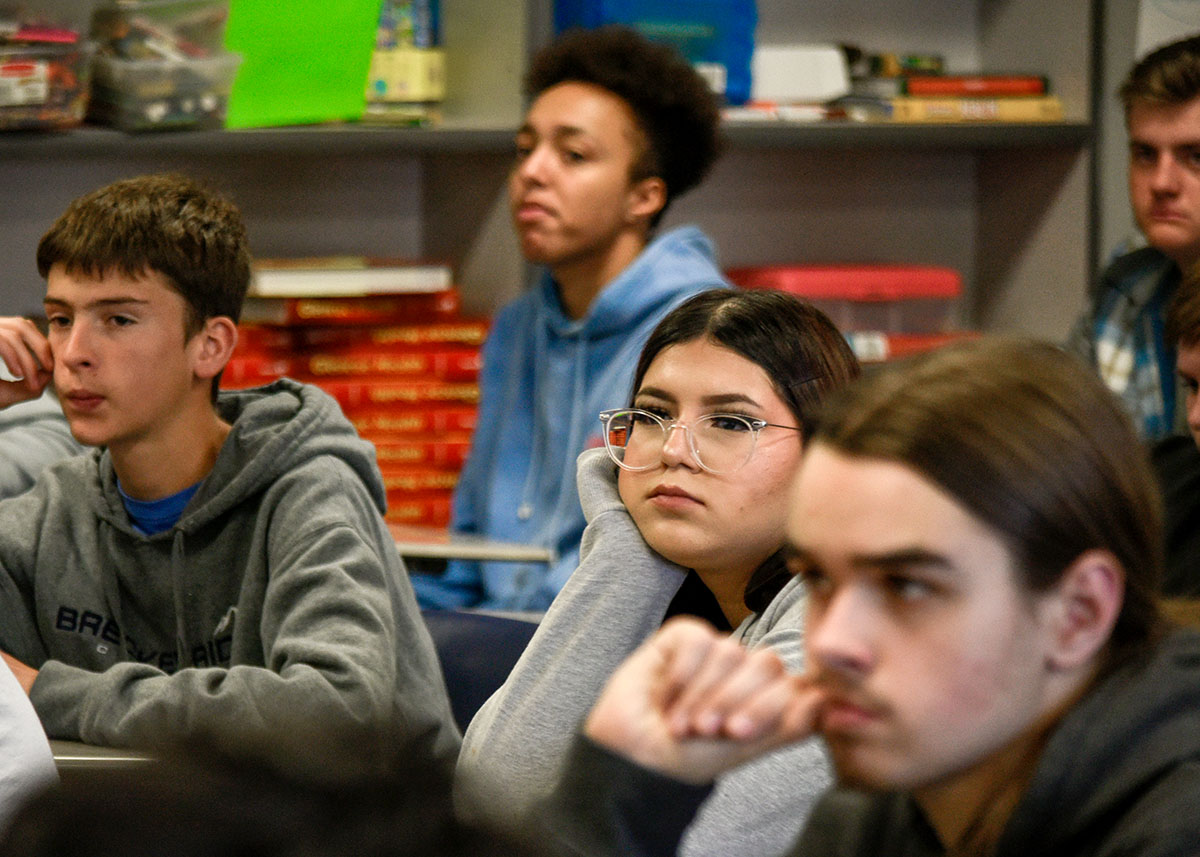 A group of youth seated in a classroom, engaged in discussion.