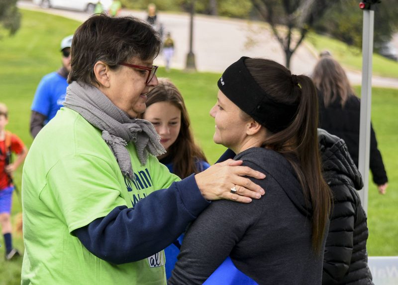 Woman with her hand on another woman's shoulder.